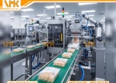 Hình ảnh một dây chuyền sản xuất thực phẩm tự động hiện đại trong nhà máy. Các sản phẩm đang được đóng gói nhanh chóng và chính xác trên băng chuyền. Môi trường sản xuất sạch sẽ, chuyên nghiệp, thể hiện hiệu quả và năng suất cao.